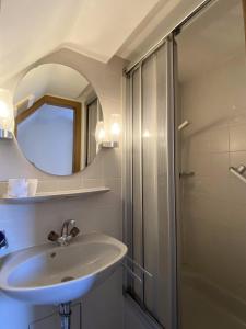 a bathroom with a sink and a shower with a mirror at Hotel & Hostel Albstadt in Albstadt