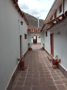 an alley between two white buildings with potted plants at Casona Buenavista Andahuaylillas in Andalmailillas
