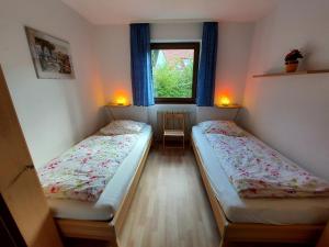 2 camas en una habitación pequeña con ventana en Ferien­wohnung Baumann, en Pleinfeld