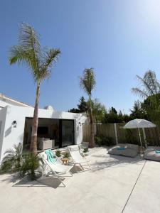 un patio con sillas, TV y una palmera en Casa Duende, Estepona, Private beach house, en Estepona