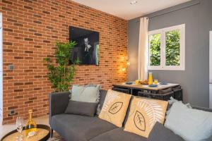 a living room with a couch and a brick wall at SUPERBE APPARTEMENT AVEC BALCON PROCHE MONACO in Beausoleil