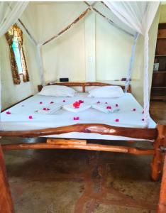 a bed with flowers on it in a room at African Dream Cottages - Diani Beach in Diani Beach