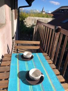 a table with two hats and cups on a balcony at Appartement dans la vieille ville, en face du château in Annecy