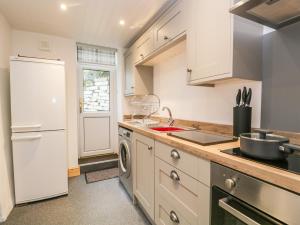 cocina con nevera blanca y fregadero en Fellside Cottage, en Cockermouth