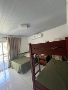 1 dormitorio con 2 camas, escritorio y ventana en MARAGOGI FLAT BEIRA MAR en Maragogi