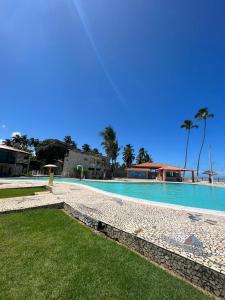a large swimming pool with blue water and palm trees at MARAGOGI FLAT BEIRA MAR in Maragogi