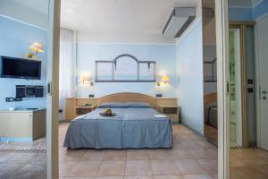 1 Schlafzimmer mit einem Bett, einer Küche und einem TV in der Unterkunft Hotel Universo in Lido di Jesolo