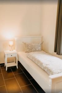 a bedroom with a white bed and a side table at Haus Hilde Zarrentin am Schaalsee in Zarrentin