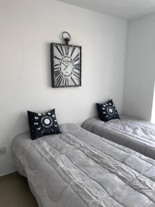 1 dormitorio con 2 camas y reloj en la pared en Dpto Nva Cba, pileta seguridad, cochera en Córdoba