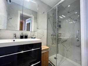 a bathroom with a sink and a glass shower at "Rue Longue" Vue Mer, Spacieux, Rénové in Menton