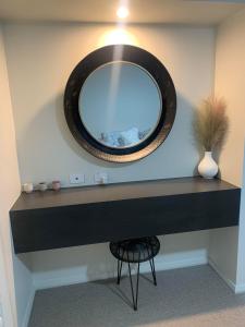 a mirror on a wall above a black desk at Huntlee Getaway in Branxton