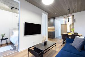 uma sala de estar com um sofá azul e uma televisão em City Center Sanctuary Modern Studio with Electric Car-Friendly Features in Vilnius em Vilnius