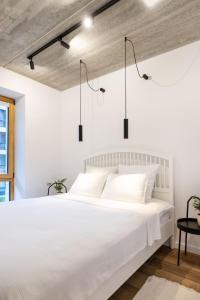 a white bedroom with a large white bed with two lights at City Center Sanctuary Modern Studio with Electric Car-Friendly Features in Vilnius in Vilnius