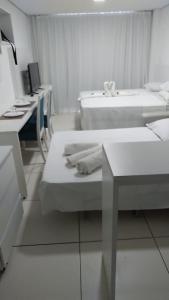 a white room with two beds and a desk at Porto de Galinhas no Laguna in Porto De Galinhas