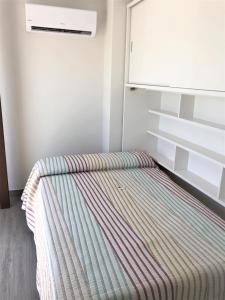 uma cama num quarto ao lado de um frigorífico em Luxury Attics Plaza Punto PARKING INCLUIDO em Huelva