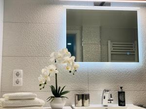 a bathroom with a vase with white flowers on a sink at Traumperle in Erfurt