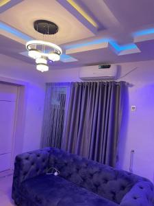 un salon avec un canapé et un plafond avec des lumières violettes dans l'établissement GS HOMES, à Lagos