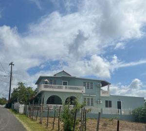 une maison bleue avec une clôture devant elle dans l'établissement Playa y Campo Getaway Apartment, with Hot Tub, à Isabela
