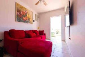 un sofá rojo en una sala de estar con una pintura en la pared en Playa y Campo Getaway Apartment, with Hot Tub, en Isabela