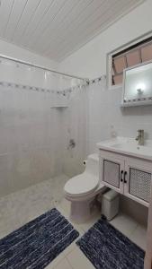 a white bathroom with a toilet and a sink at Playa y Campo Getaway Apartment, with Hot Tub in Isabela