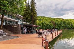 personas sentadas en mesas en un muelle junto a un lago en Adventure Lake Resort - Simared, en Baia Mare