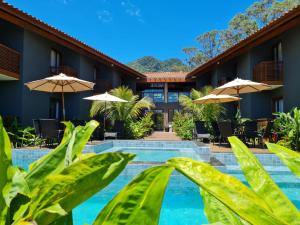 a resort with a swimming pool and umbrellas at Pousada Vila Ipuan in Pauba