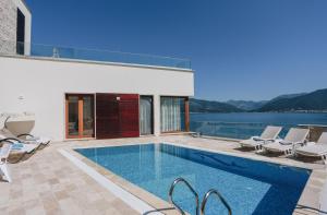 a swimming pool with chairs and a house at Villa Semiramis in Tivat