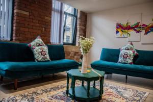 ein Wohnzimmer mit 2 blauen Sofas und einem Tisch in der Unterkunft BV Lush Apartment At Conditioning House Bradford in Bradford
