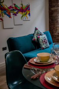 ein Wohnzimmer mit einem blauen Sofa und einem Tisch mit Geschirr in der Unterkunft BV Lush Apartment At Conditioning House Bradford in Bradford