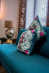eine blaue Couch mit zwei Kissen drauf in der Unterkunft BV Lush Apartment At Conditioning House Bradford in Bradford