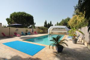 a swimming pool in a yard with chairs and tables at Le Jardin du Somail in Le Somail