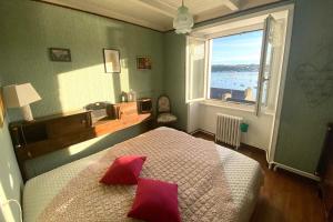 Schlafzimmer mit einem Bett mit roten Kissen und einem Fenster in der Unterkunft Locquenole house with sea view in Locquénolé