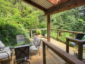 een terras met een glazen tafel en stoelen en een piano bij Rainforest Retreat in Bowen Island