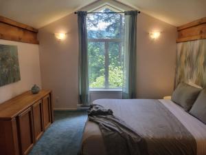 ein Schlafzimmer mit einem Bett und einem großen Fenster in der Unterkunft Rainforest Retreat in Bowen Island