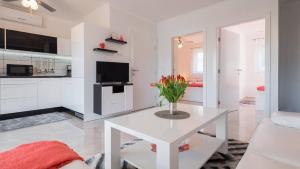 una sala de estar blanca con un jarrón de flores sobre una mesa en La Perla Apartments en Sutivan
