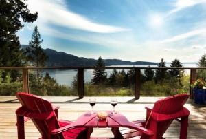 two chairs and a table with wine glasses on a deck at Evergreen Cottage in Bowen Island