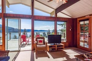 ein Wohnzimmer mit einem TV und großen Fenstern in der Unterkunft Evergreen Cottage in Bowen Island