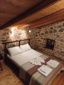 Ce lit se trouve dans un dortoir doté d'un mur en pierre. dans l'établissement ΕΥμορφο σαν παραμύθι ΑΜΥΓΔΑΛΙΑ, à Amfikleia