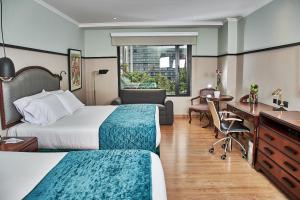 um quarto de hotel com duas camas e uma secretária em Hotel Poblado Plaza em Medellín