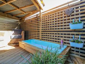 uma banheira de hidromassagem num deque de madeira com dois vasos de plantas em Lindsay Cottage em Kirriemuir