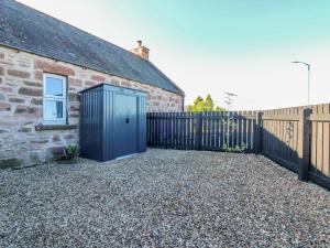 a brick house with a blue door next to a fence at Lindsay Cottage in Kirriemuir