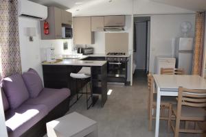 a living room and kitchen with a couch and a table at Mobilhome 526 3ch/2SDB camping 4* La Réserve SIBLU Gastes in Gastes
