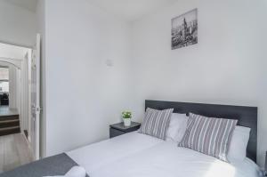 uma cama branca com almofadas listradas num quarto em The Rock House em Plumstead