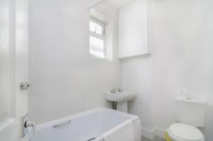 uma casa de banho branca com um lavatório e um WC em The Rock House em Plumstead