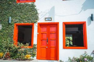 een oranje deur en twee ramen op een gebouw bij Casa Hotel El Porton SALENTO in Salento
