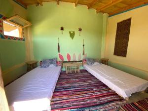 a bedroom with two beds in a room with a rug at Hidden place in Siwa