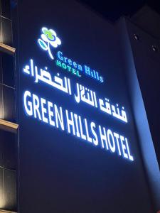 a sign for a green hills hotel on a wall at فندق التلال الخضراء in An Nimāş