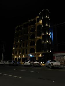 budynek z samochodami zaparkowanymi przed nim w nocy w obiekcie فندق التلال الخضراء w mieście An Nimāş