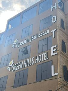 a building with a sign for green hills hotel at فندق التلال الخضراء in An Nimāş