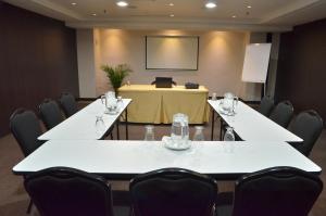 a conference room with white tables and chairs and a screen at HOTEL CHACAO SUITES in Caracas